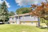 Charming suburban residence showcasing a clean, contemporary look with purple siding and tan brick accents. The symmetrical façade includes multiple w
