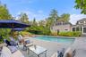 Beautifully landscaped pool area with firepit, gas grill, outdoor speakers, and ample space for family and guest entertainment