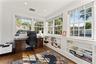 Primary bedroom office/sunroom lined with windows and enclosed with a pocket door for privacy
