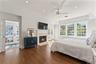Luxurious sun-filled primary suite with gas fireplace, a pocket door for privacy to a window-lined office/sunroom and a door to the deck for outdoor r