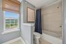 Bathroom featuring a window with a mountain backdrop, a full bathtub with a shower, textured wall tile, and light wood-finish flooring