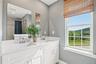 Bright bathroom featuring a double vanity with white cabinetry and light countertops.
