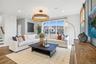 Spacious living area featuring large windows, wood-finish flooring and  recessed lighting.