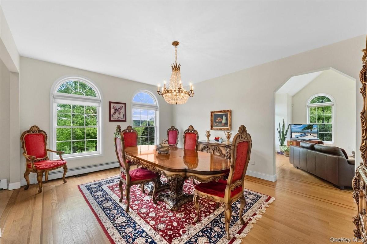 Dining room with hanging lights, light wood-type flooring, arched walkways, and vaulted ceiling