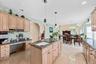 Kitchen with light wood finish cabinets, dark stone counters, arched walkways, and vaulted ceiling