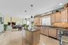 Kitchen featuring light wood finish cabinets, dark stone counters, paneled dishwasher, gas stove, and a center island
