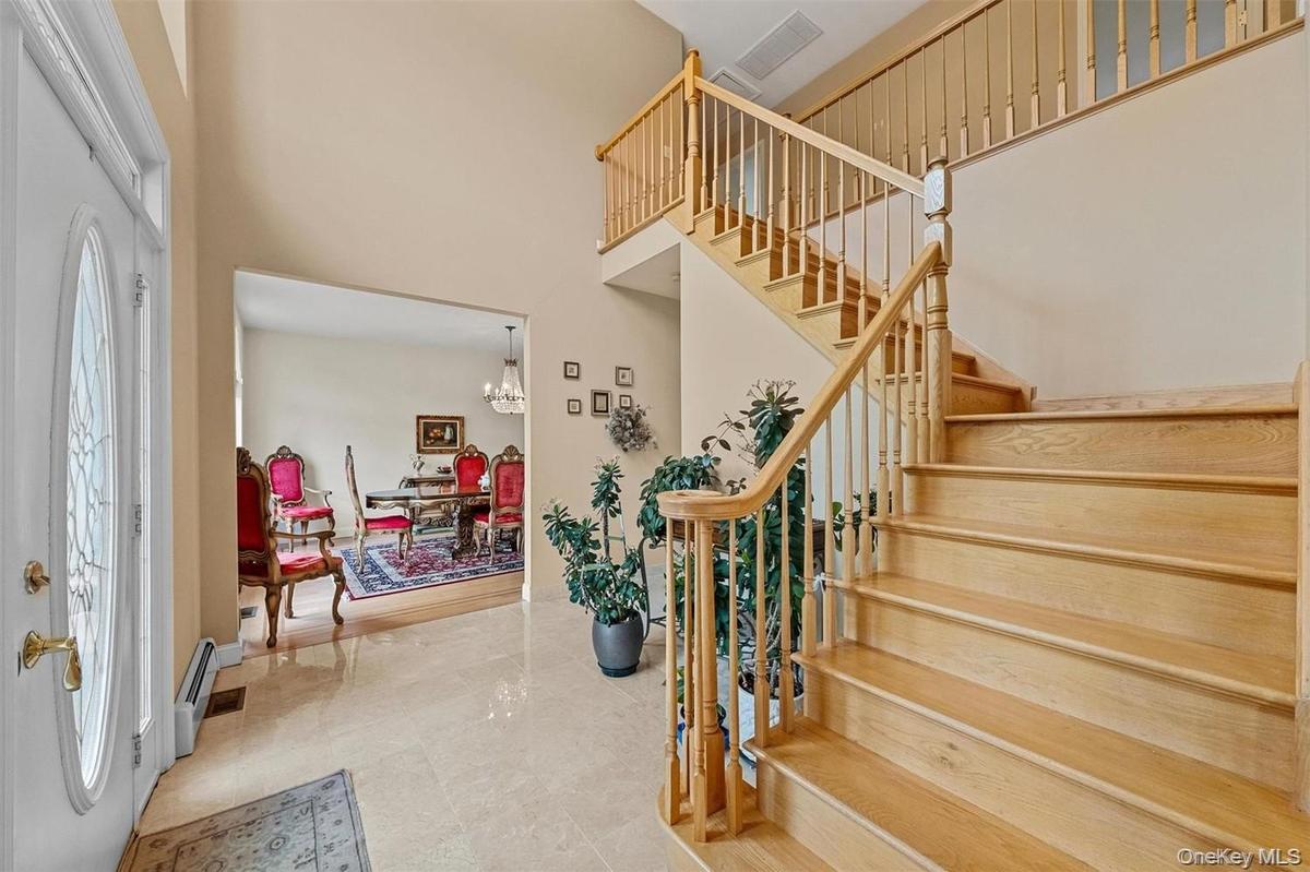 Foyer with suspended lighting, a high ceiling, and a baseboard heating unit