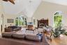 Living room with a high ceiling, light wood finished floors, a fireplace, ceiling fan, and arched walkways