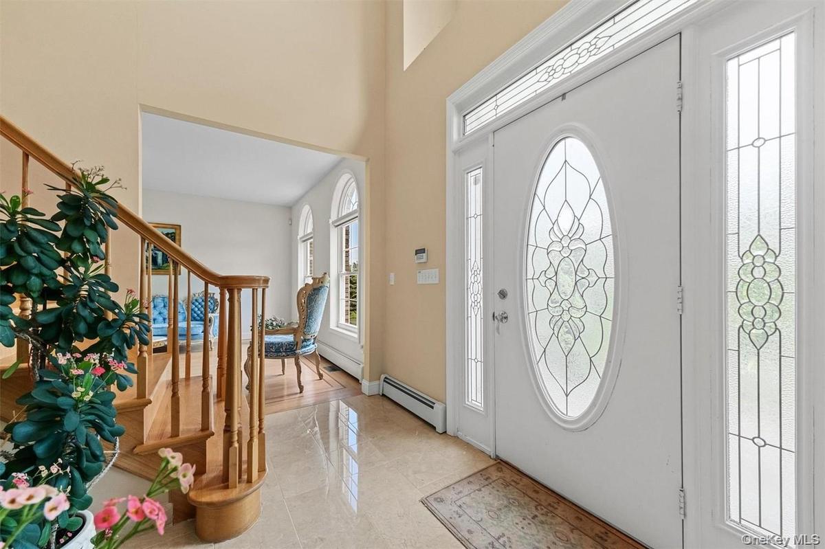 Foyer featuring a baseboard heating unit, a high ceiling, and light tile patterned floors