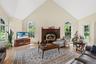 Living room with a high ceiling, light wood finished floors, baseboard heating, and a high end fireplace