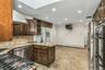 Kitchen featuring dark brown cabinetry, open shelves, light stone counters, backsplash, and recessed lighting