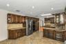 Kitchen featuring glass insert cabinets, backsplash, light stone countertops, dark brown cabinetry, and a skylight