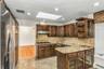 Kitchen with a skylight, stainless steel appliances, open shelves, dark brown cabinets, and recessed lighting