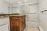 Bathroom featuring combined bath / shower with glass door, vanity, baseboard heating, tile walls, and light tile patterned floors
