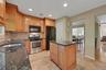 Kitchen featuring wood cabinetry, stainless steel range, built-in microwave, and a central island with a dark granite countertop