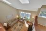 Vaulted ceilings with multiple skylights, hardwood flooring, and large windows with privacy blinds