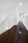 Dark wood-finish flooring with white baseboards and recessed lighting