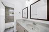Bathroom featuring a dual vanity with integrated sinks, framed mirrors, wood-finish flooring, and a shower/tub combination with a tiled surround