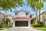 Two-story stucco exterior with a red barrel tile roof, integrated garage, and manicured landscaping