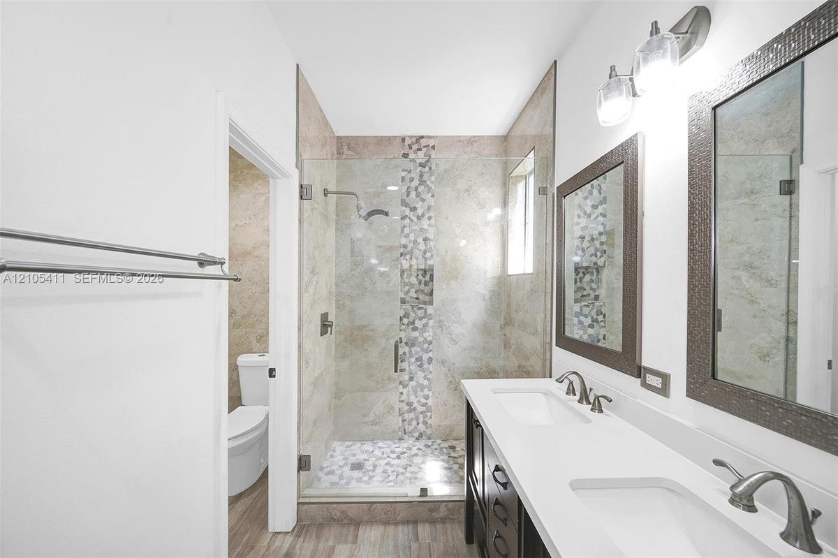 Walk-in glass-enclosed shower with pebble floor and mosaic tile accent
