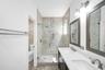 Walk-in glass-enclosed shower with pebble floor and mosaic tile accent