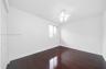 Dark wood-finish flooring, white walls, built-in closet with bi-fold doors, single window with horizontal blinds, and a ceiling fan with light fixture