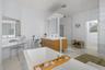 Freestanding bathtub with deck-mounted faucet, dual vanity with wood-finish cabinetry, built-in makeup vanity, glass-enclosed shower, and tiled floori