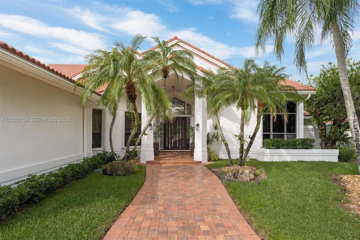 Red tile roof, stucco exterior, paver walkway, mature palm trees, and established landscaping