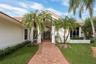 Red tile roof, stucco exterior, paver walkway, mature palm trees, and established landscaping