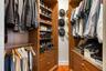 Custom closet system featuring wood-finish cabinetry, integrated shelving, and multiple hanging rods