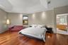 Tray ceiling with recessed lighting, wood-finish flooring, and an adjoining bathroom featuring a dual vanity