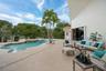 Shaped pool with integrated spa, expansive patio, mature palm trees, and sliding glass doors