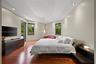 Tray ceiling with recessed lighting, wood-finish flooring, two large windows, built-in media console, and a glass-paneled door