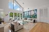 High vaulted ceiling, upper transom windows, multiple French doors, natural stone flooring, and wood-finish flooring