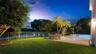 Expansive lawn with a metal fence, bordering a body of water