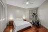 Wood-finish flooring, louvered bi-fold closet doors, window with louvered shutters, and ceiling fan with integrated lighting