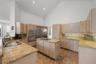 Kitchen featuring high vaulted ceilings, light wood-finish cabinetry, granite countertops, a stainless steel refrigerator, and a kitchen island with c