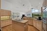 Vaulted ceiling with recessed lighting and a ceiling fan, integrated double oven, and a built-in cooktop on a central island