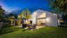 Expansive lawn with mature palm trees, a concrete patio, and large glass sliding doors