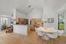 Vaulted ceilings with recessed lighting, wood-finish flooring, kitchen with light wood cabinetry, stone countertops, and stainless steel appliances