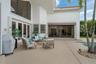 Extensive concrete patio featuring a curved swimming pool, full-height glass doors, and hurricane shutters