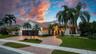Stucco exterior, barrel tile roof, paver driveway, mature palm trees, integrated garage