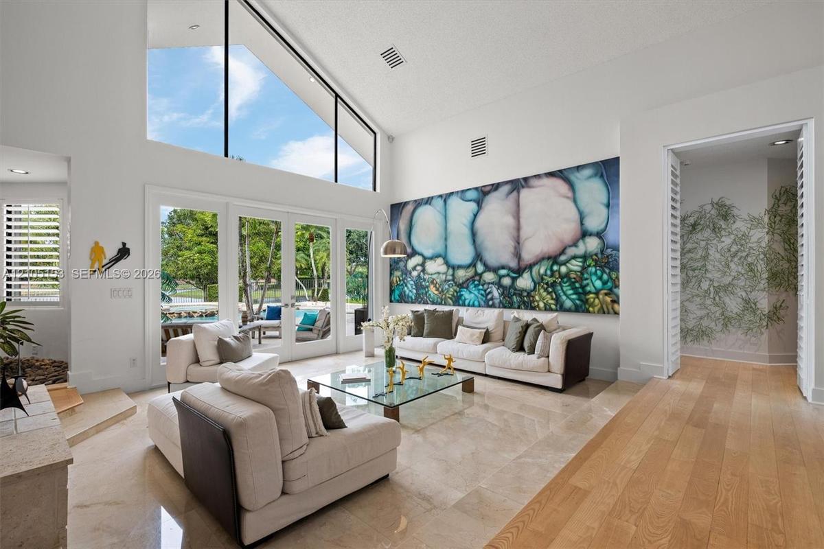 Vaulted ceilings with clerestory windows, expansive glass doors, polished stone flooring, wood-finish flooring, and a built-in stone hearth