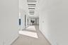 Expansive hallway featuring floor-to-ceiling glass doors, large format tile flooring, contemporary linear chandeliers, and recessed lighting