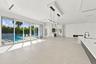 Sophisticated open-concept living space featuring polished light-toned stone flooring, floor-to-ceiling multi-panel glass doors and windows overlookin