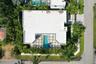 Aerial view showcasing a modern residence with a flat roof, clean white exterior, and a striking turquoise swimming pool surrounded by a dark-finished