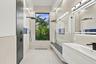 Spa-inspired primary bathroom featuring dual vanities with white cabinetry, quartz countertops, and matte black fixtures