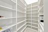 Spacious pantry featuring extensive built-in shelving with adjustable shelves throughout, white finish cabinetry, and bright overhead lighting
