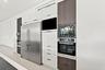 Contemporary kitchen featuring stainless steel dual-door refrigerator, integrated wall-mounted oven and microwave, flat-panel cabinetry in white and w