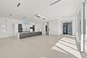 Spacious open-concept interior featuring light-toned flooring, a full-height glass door, and recessed lighting